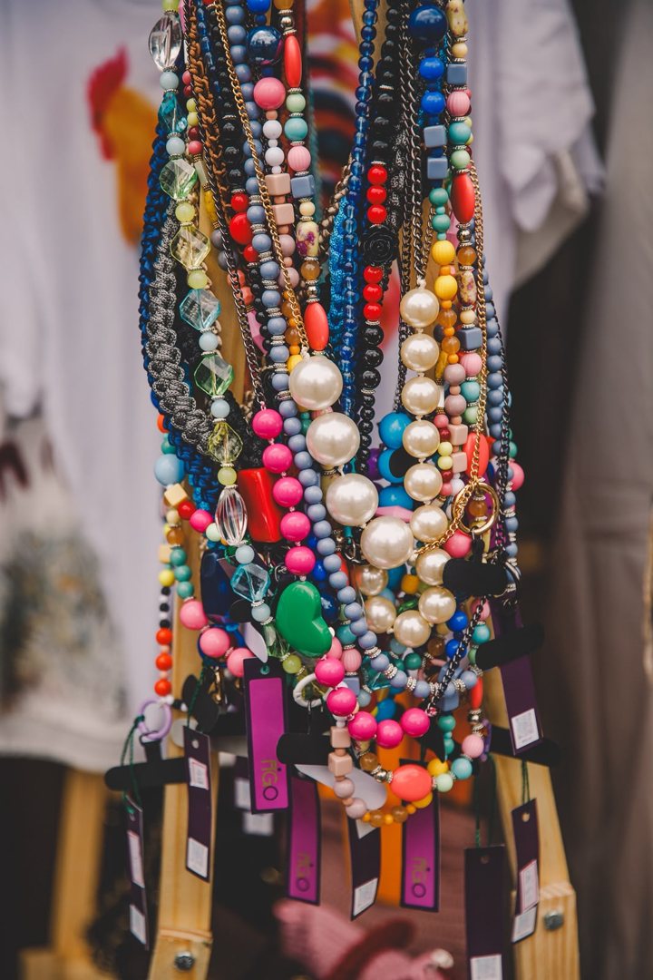 Colares de contas coloridas e pérolas pendurados num expositor de madeira